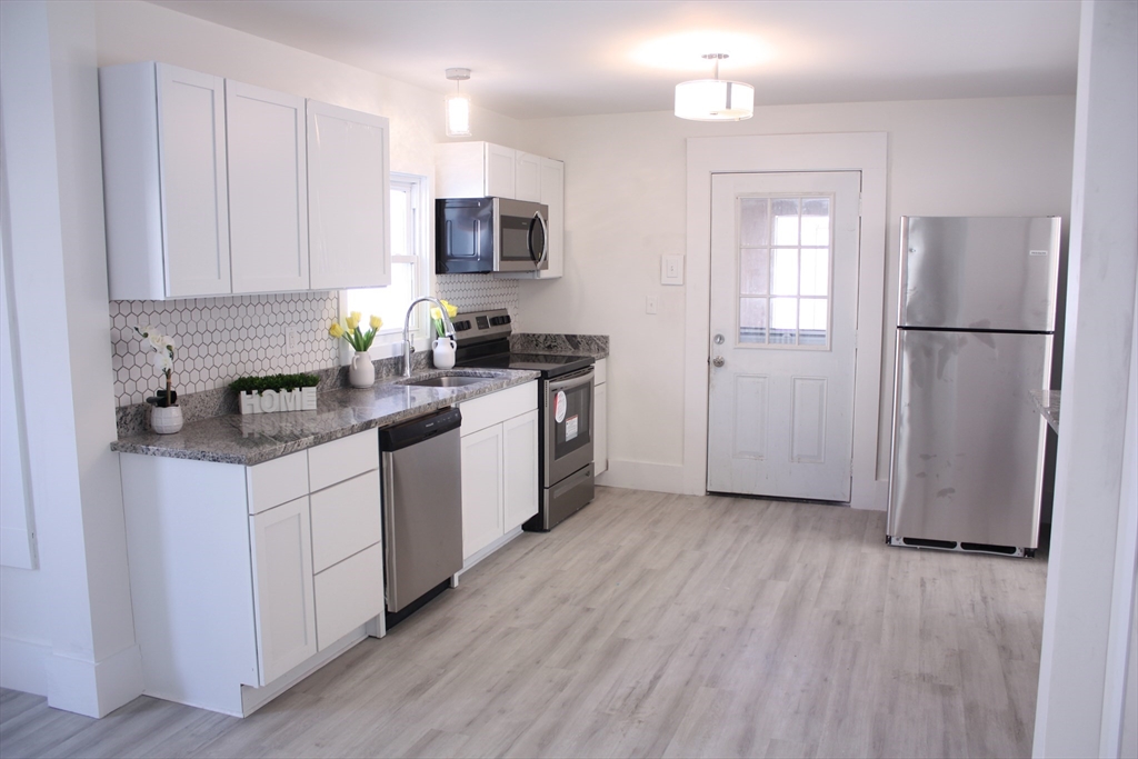 23 Foster Street Springfield, MA 01105 - Photo 3 of 15 a kitchen with a refrigerator a sink and wooden floor