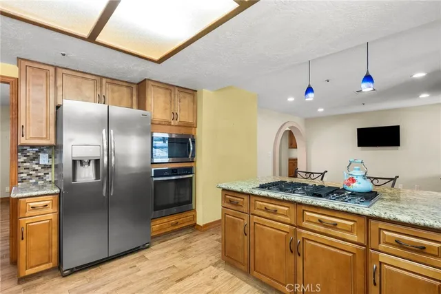 a kitchen with stainless steel appliances granite countertop a refrigerator a stove and a sink with wooden floor