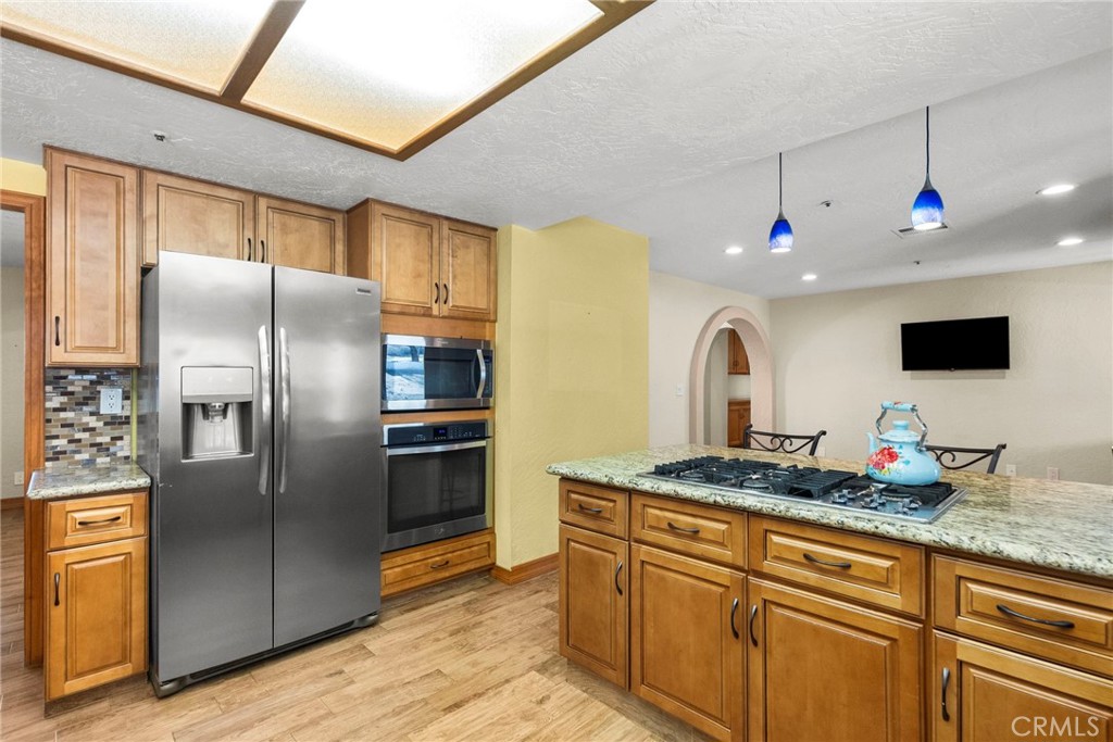902 Searchlight Ranch Road Acton, CA 93510 - Photo 11 of 52 a kitchen with stainless steel appliances granite countertop a refrigerator a stove and a sink with wooden floor