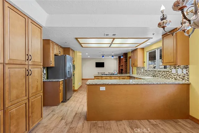 a kitchen with stainless steel appliances granite countertop a refrigerator a stove and a wooden floors