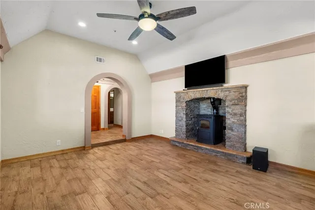 a view of an empty room with a fireplace and a ceiling fan