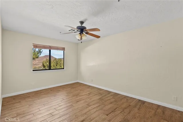 a view of a livingroom with a chandelier fan and wooden floor