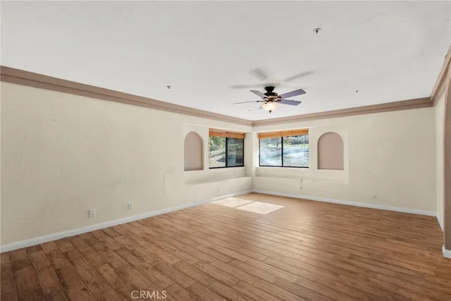 a view of empty room with wooden floor and fan