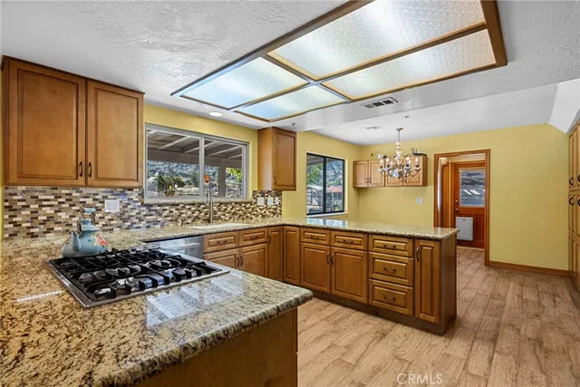 a kitchen with stainless steel appliances granite countertop a stove a sink dishwasher and cabinets with wooden floor