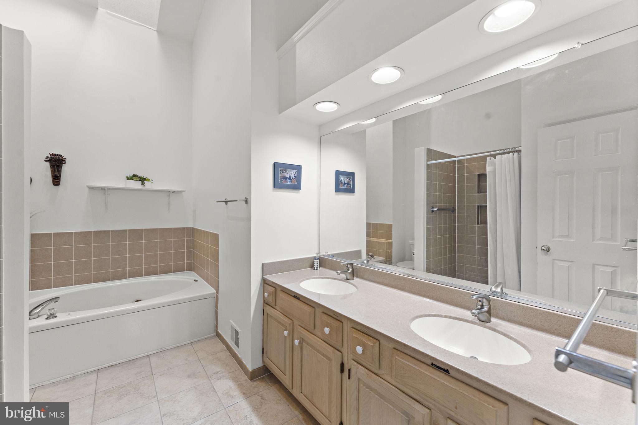 10934 Rocky Mt Way Silver Spring, MD 20902 - Photo 28 of 51 a bathroom with a granite countertop tub sink a mirror and a bathtub