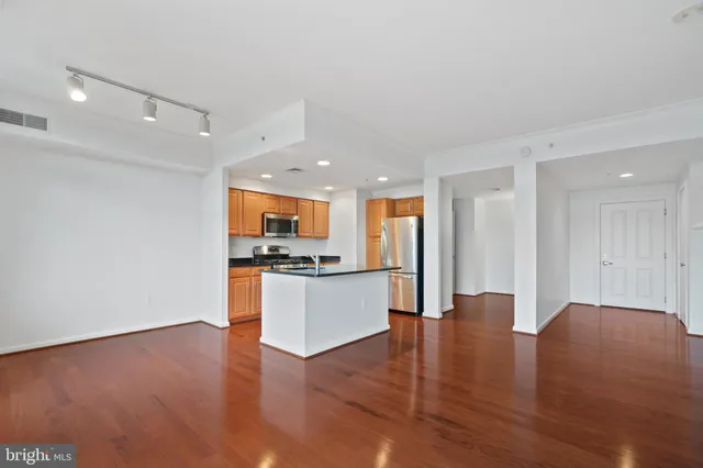 a view of a kitchen with kitchen island wooden floor appliances and living room