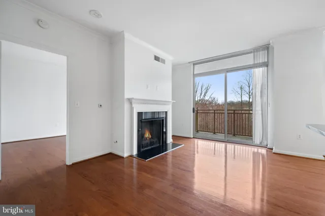 an empty room with wooden floor fireplace and windows