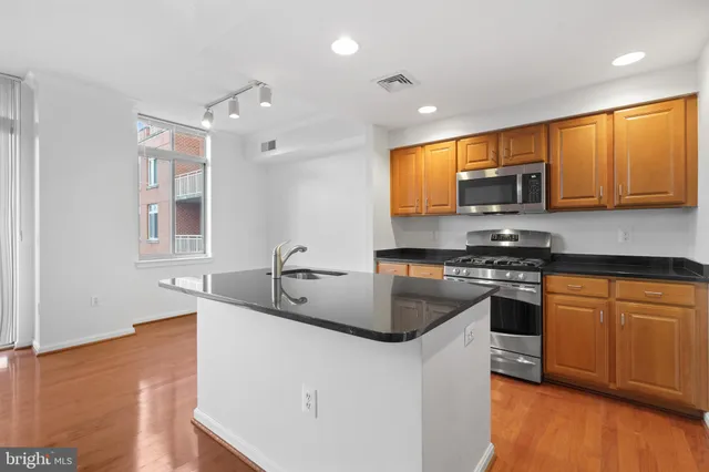 a kitchen with stainless steel appliances granite countertop a sink a stove a microwave a counter top space and cabinets