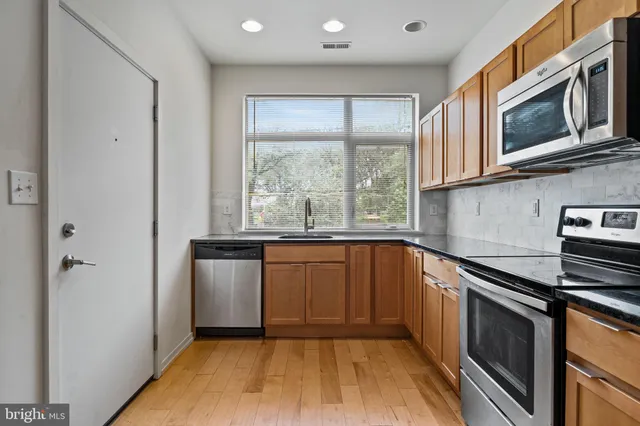 a kitchen with granite countertop a stove a sink and a microwave