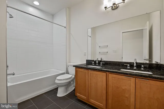 a bathroom with a granite countertop sink a toilet a mirror and shower
