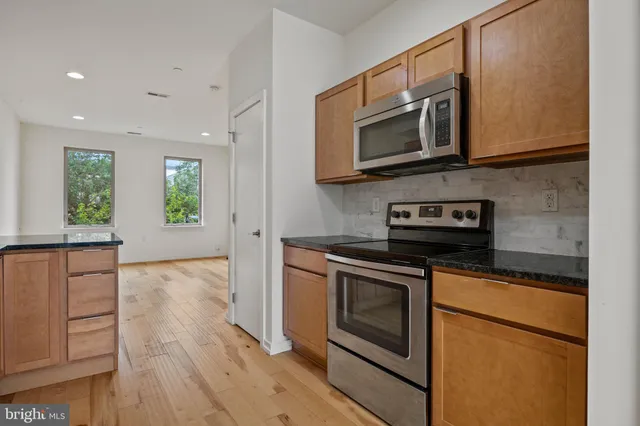 a kitchen with stainless steel appliances granite countertop a stove a microwave and a white cabinets