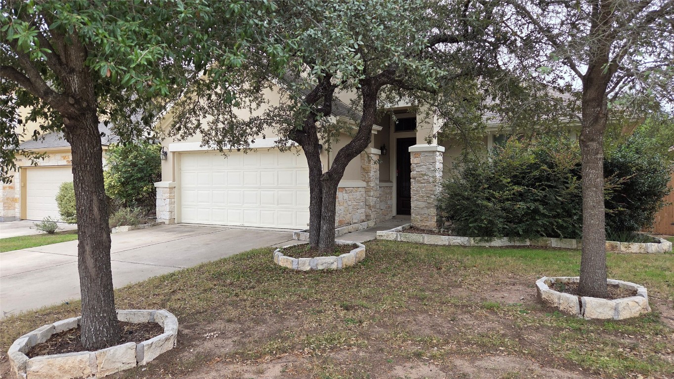 2216 Lookout Range Drive Leander, TX 78641 - Photo 2 of 16 View of property hidden behind natural elements featuring driveway, stone siding, and stucco siding