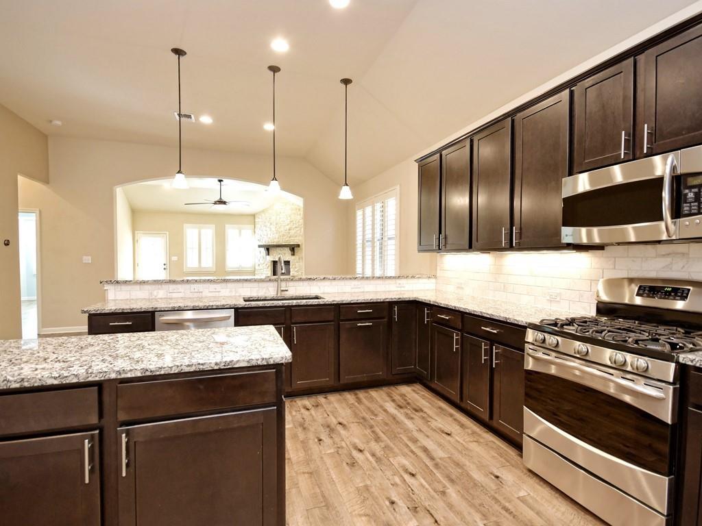 2216 Lookout Range Drive Leander, TX 78641 - Photo 4 of 16 Kitchen with dark brown cabinetry, appliances with stainless steel finishes, a peninsula, hanging light fixtures, and a ceiling fan