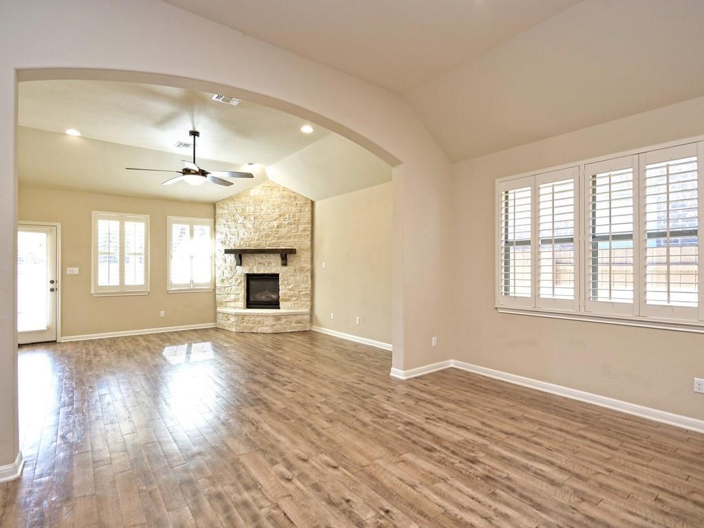 2216 Lookout Range Drive Leander, TX 78641 - Photo 7 of 16 Unfurnished living room featuring a ceiling fan, lofted ceiling, a fireplace, light wood finished floors, and recessed lighting