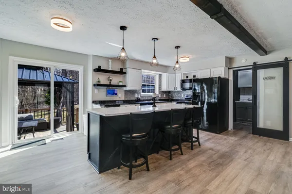 a kitchen with stainless steel appliances granite countertop a refrigerator a sink dishwasher a stove and a dining table with wooden floor