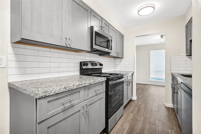 a kitchen with stainless steel appliances granite countertop a stove and a wooden cabinets
