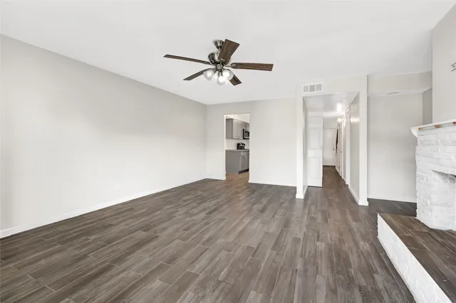 a view of a room with wooden floor a ceiling fan and kitchen space