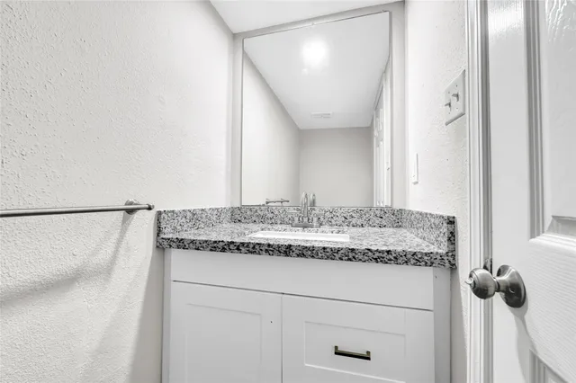 a bathroom with a granite countertop sink and a mirror