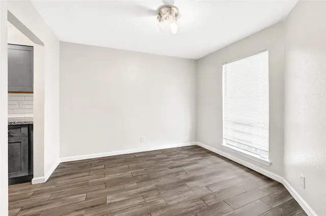 an empty room with wooden floor cabinet and windows