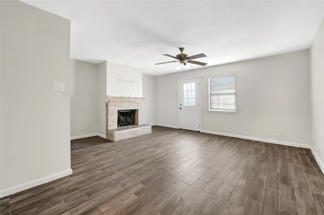an empty room with wooden floor fireplace and windows