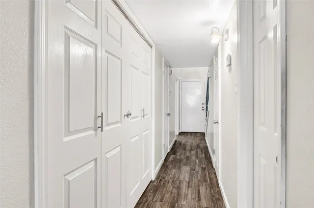a view of a hallway with wooden floor and closet area