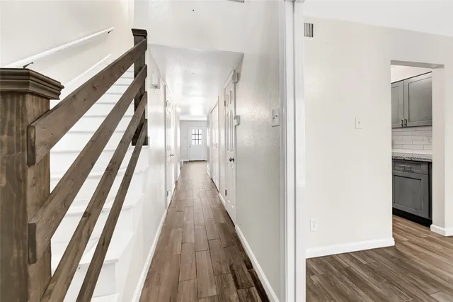 a view of a hallway with wooden floor and staircase