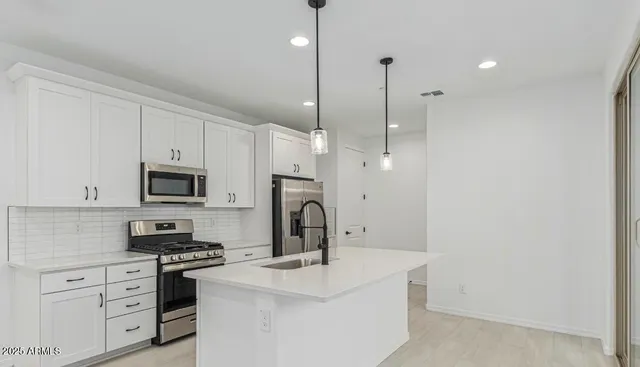 a kitchen with stainless steel appliances a stove a sink and white cabinets