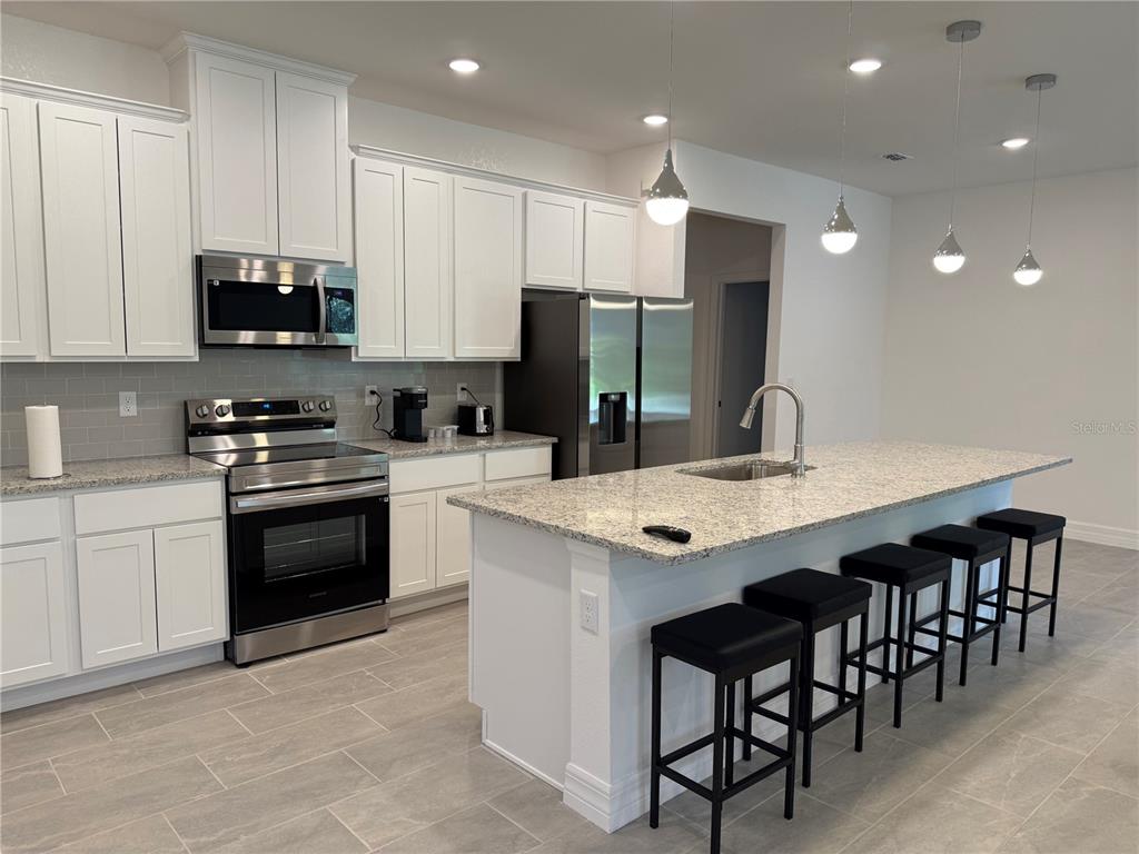 15467 Maynard Avenue Port Charlotte, FL 33953 - Photo 2 of 13 a kitchen with stainless steel appliances granite countertop a stove a sink a microwave a refrigerator and white cabinets