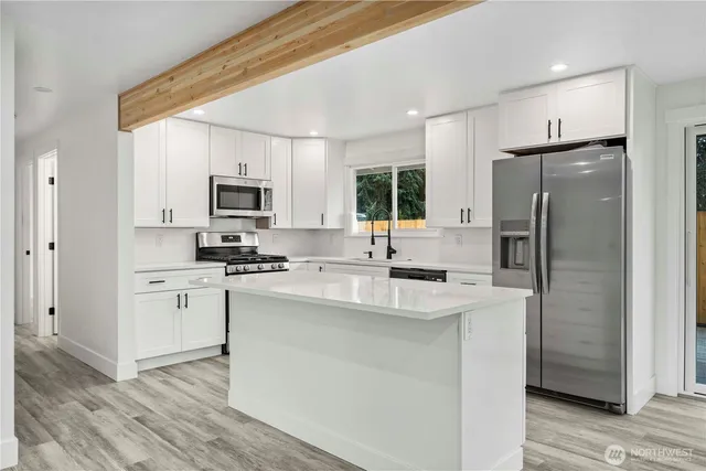 a kitchen with stainless steel appliances granite countertop a refrigerator sink stove microwave and cabinets