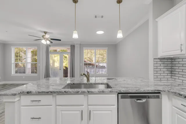 a kitchen with granite countertop a sink and white cabinets