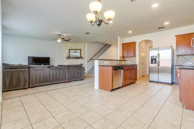 a kitchen with stainless steel appliances granite countertop a refrigerator and a view of living room