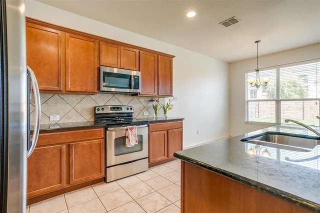 a kitchen with granite countertop a sink cabinets and stainless steel appliances