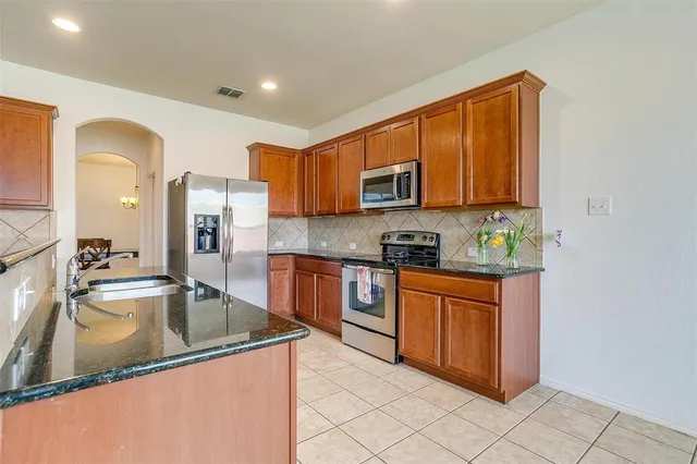 a kitchen with stainless steel appliances granite countertop a sink a stove and a refrigerator