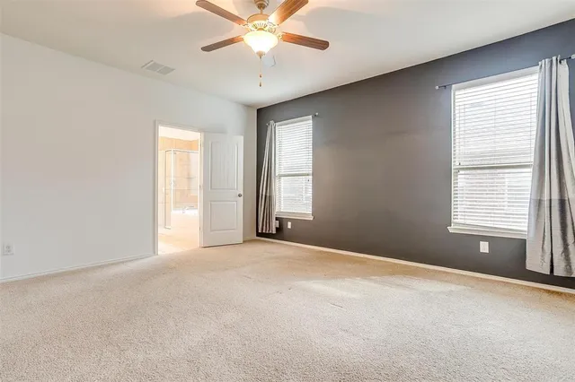an empty room with windows and fan