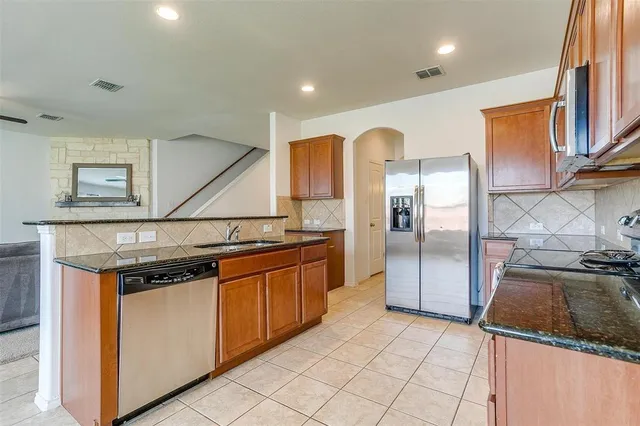 a kitchen with stainless steel appliances granite countertop a stove a refrigerator and a sink