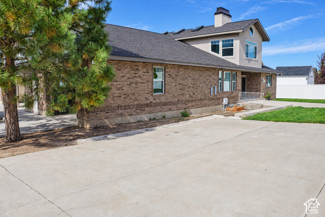580 North 300 East Logan, UT 84321 - Photo 64 of 96 Brick exterior with stucco accents, dark shingle roof, multiple windows, and a paved concrete surface