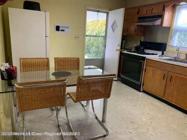 a kitchen with stainless steel appliances kitchen island granite countertop a refrigerator a stove a sink dishwasher and white countertops with wooden floor