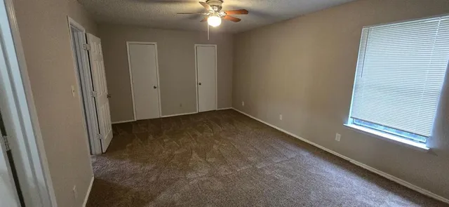en empty room with windows and chandelier fan