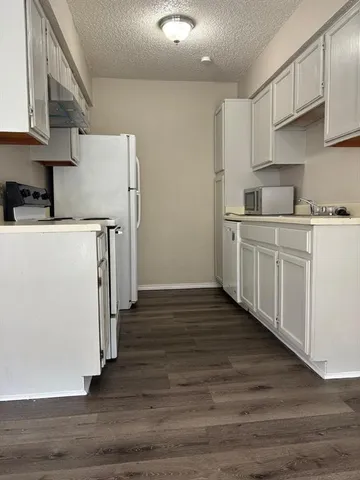 a kitchen with wooden floor and white stainless steel appliances