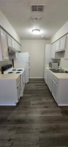 a kitchen with stainless steel appliances a stove a sink and white cabinets