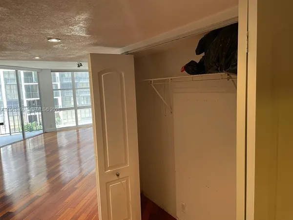 a view of a hallway with wooden floor and a cabinet