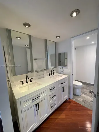 a bathroom with a double vanity sink and mirror with toilet