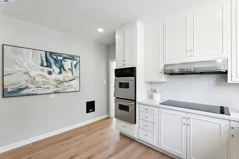 a kitchen with stainless steel appliances white cabinets and a wooden floor
