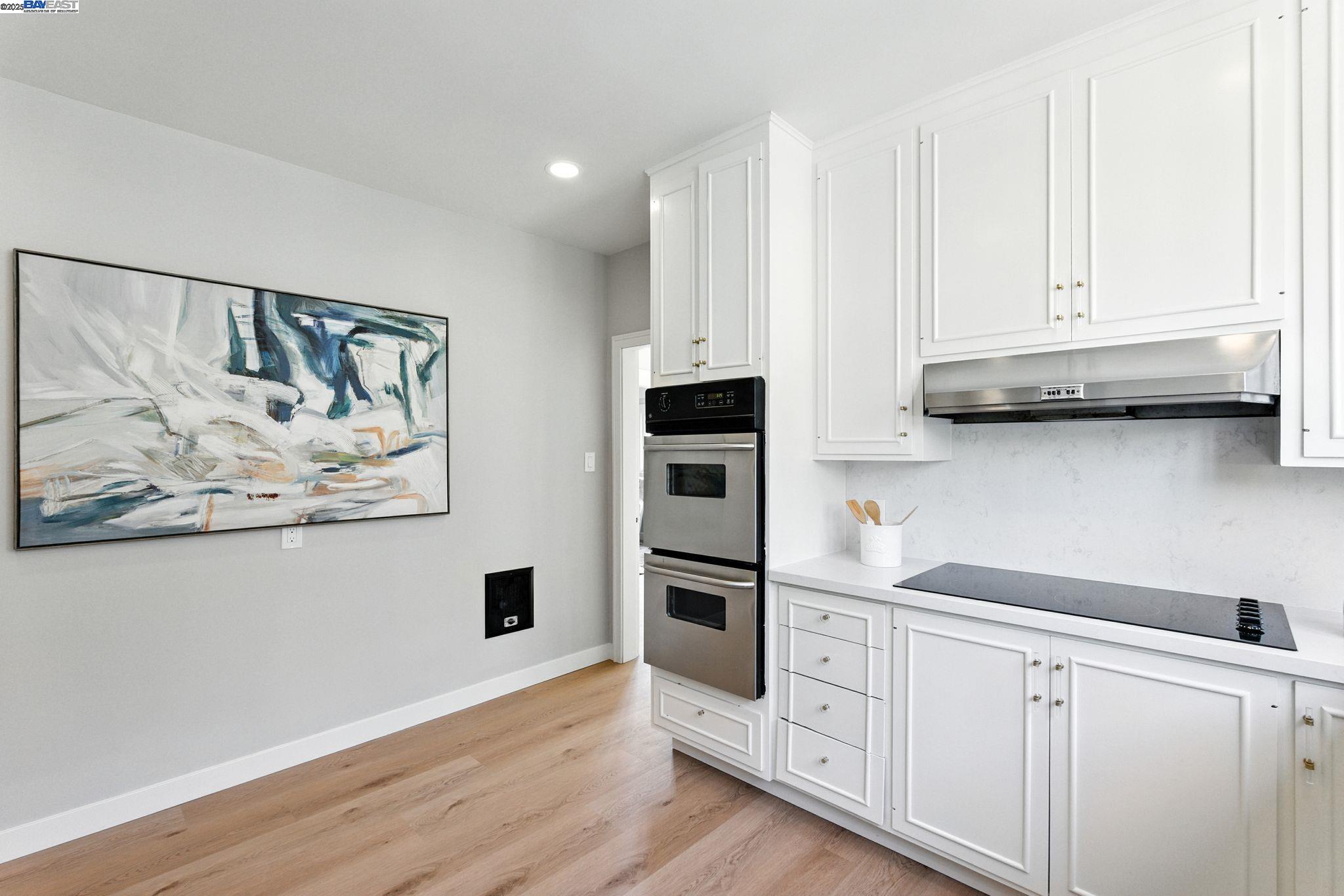 1247 Sherman Street Alameda, CA 94501 - Photo 19 of 50 a kitchen with stainless steel appliances white cabinets and a wooden floor