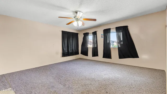 a view of an empty room with chandelier fan