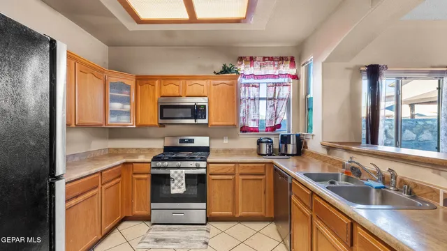 a kitchen with stainless steel appliances a stove sink microwave and window