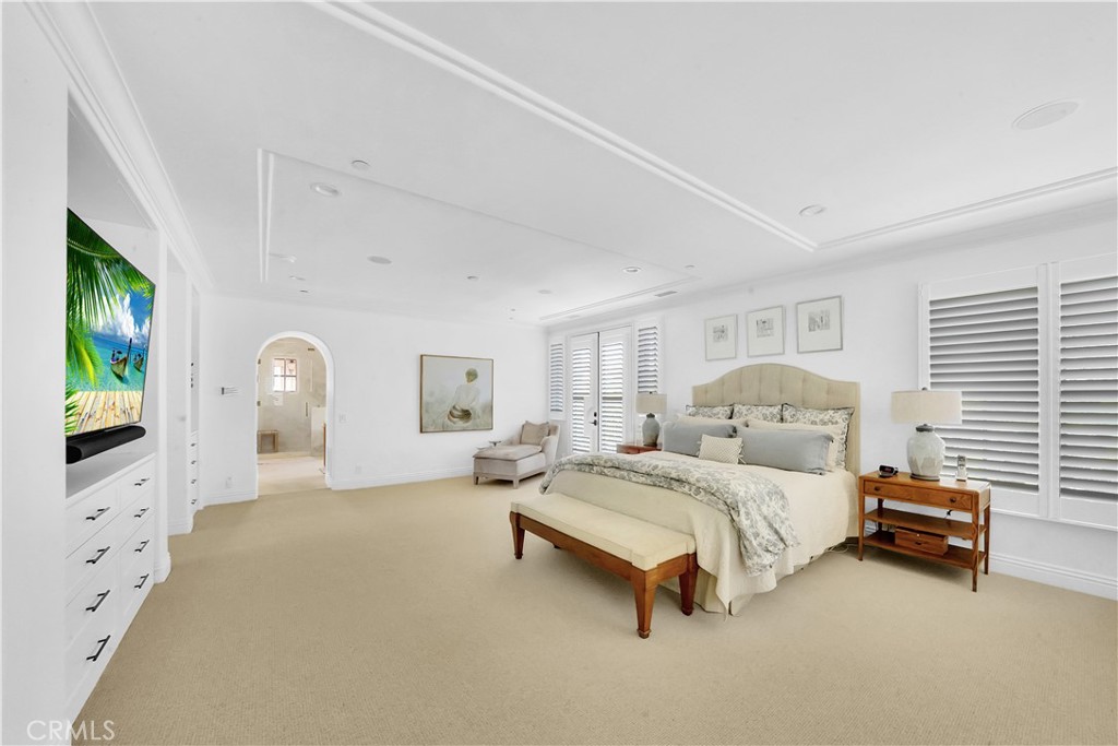 11 Hidden Pass Newport Coast, CA 92657 - Photo 43 of 59 a spacious bedroom with a bed a mirror on dresser and a chandelier