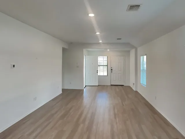 an empty room with wooden floor and windows