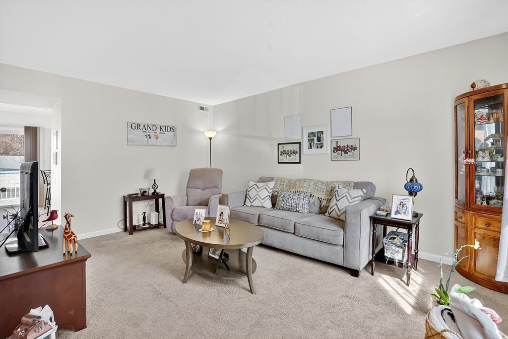 80 Yorktown Drive, Unit 80 Springfield, MA 01108 - Photo 4 of 24 a living room with furniture a flat screen tv and a wall painting