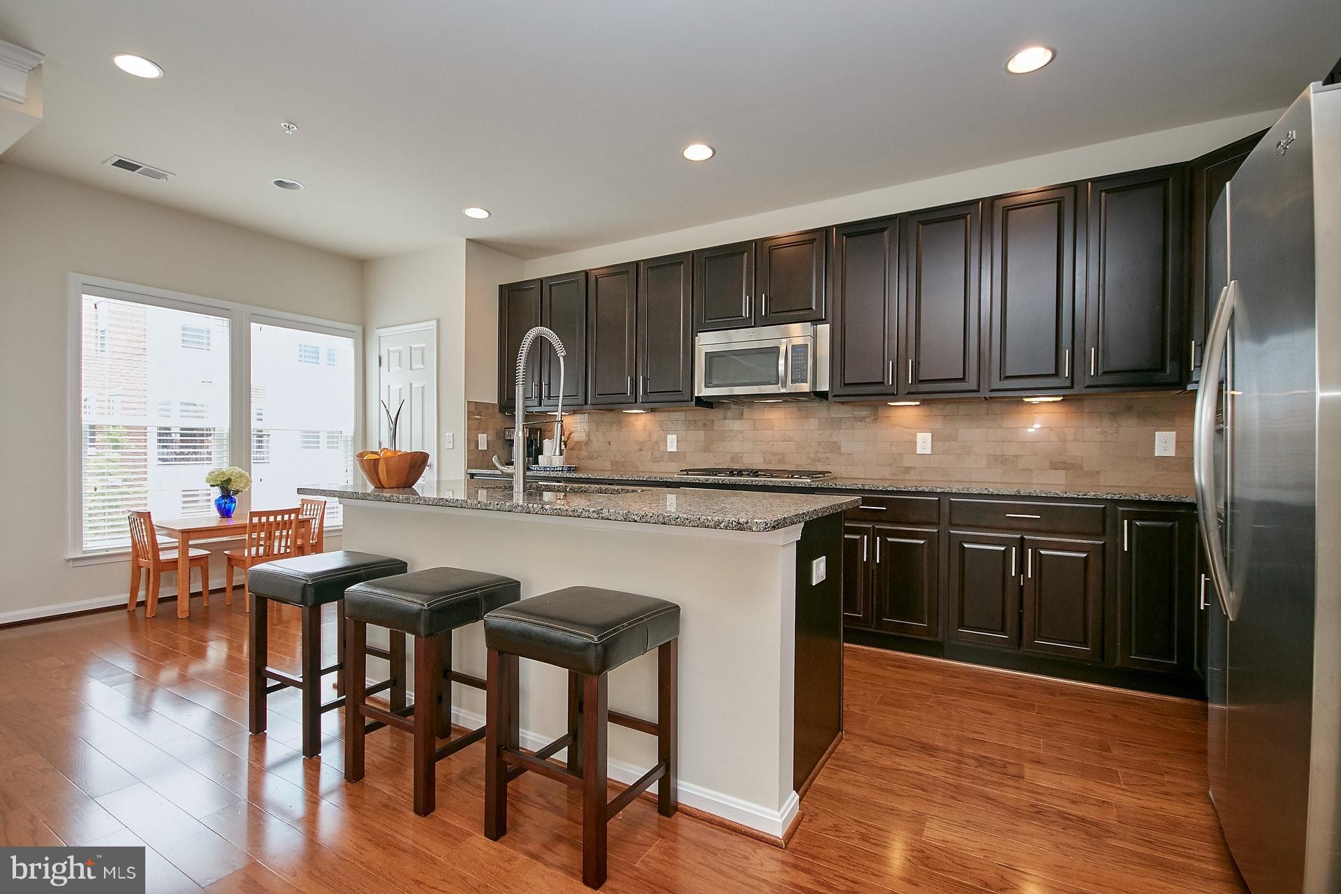 3073 Rittenhouse Circle, Unit 60 Fairfax, VA 22031 - Photo 9 of 30 a kitchen with kitchen island granite countertop wooden floors and wooden cabinets